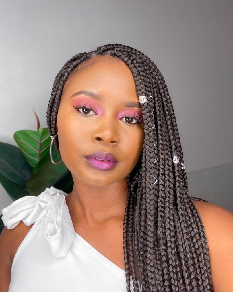 Long side swept box braids with silver hair cuffs and neat medium sized braids.