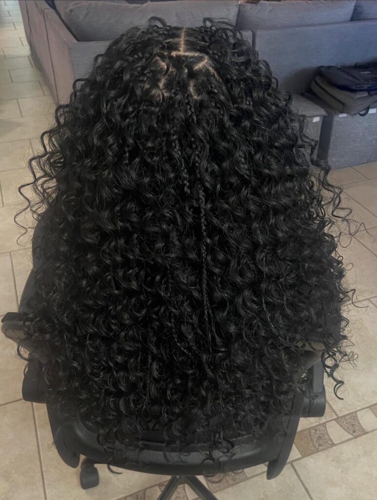 Black curly braids with voluminous spiral curls and small braided sections.