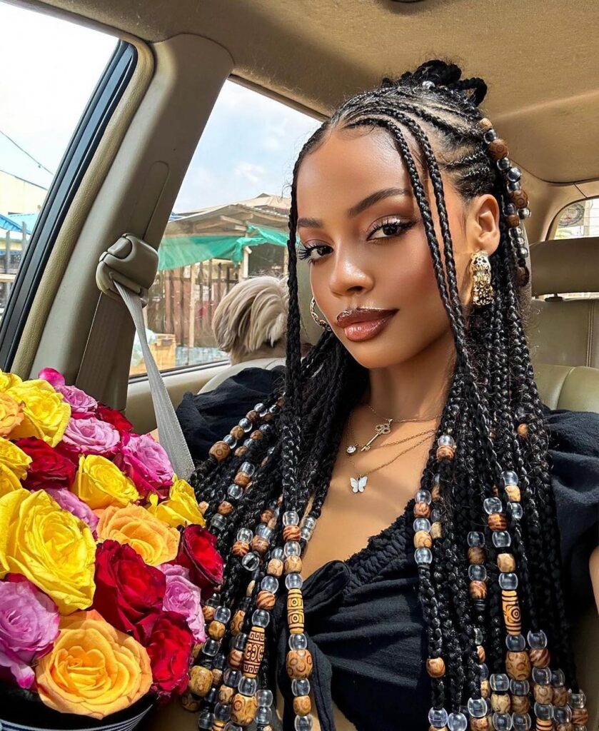 Fulani braids with wooden and clear beads styled in a half up braided look.