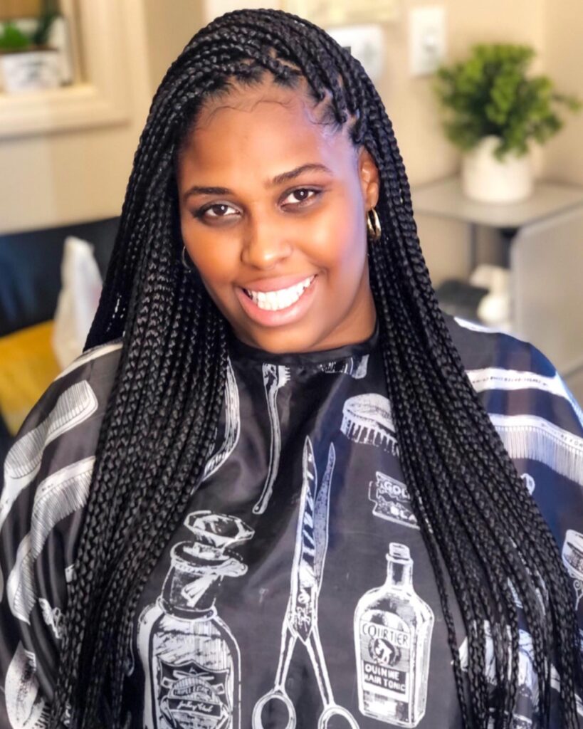 Long jumbo black braids styled with a deep side part.