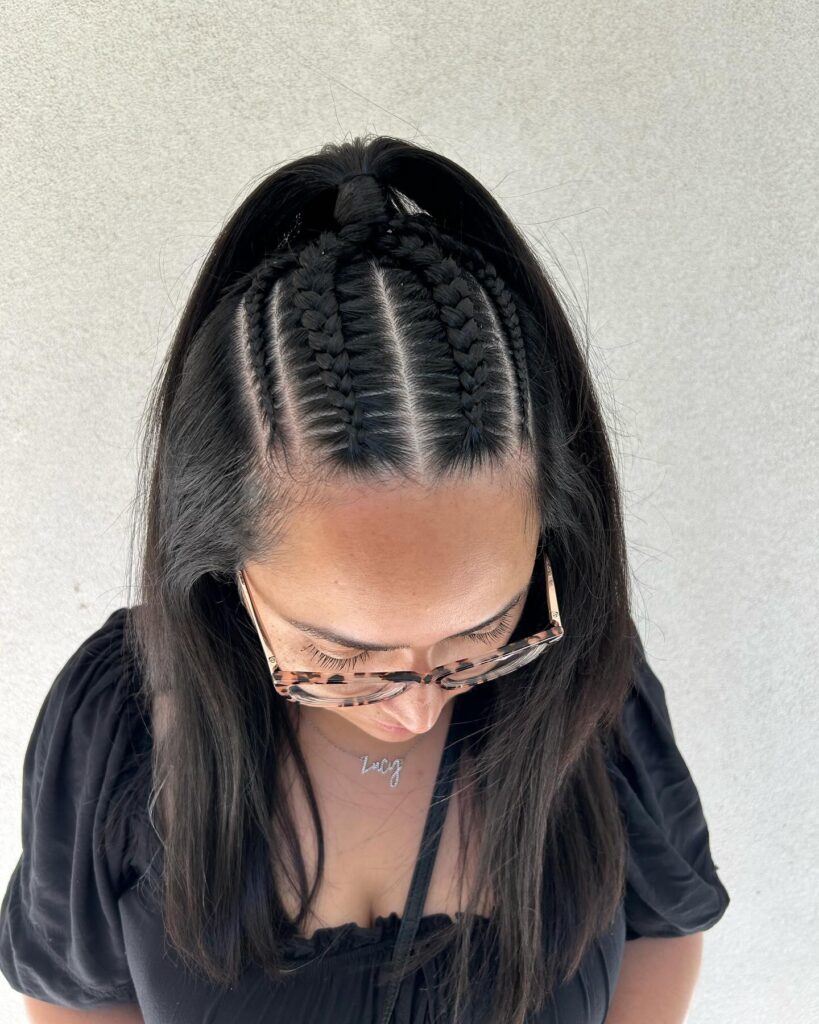 Dark straight hair styled with center braids and a sleek half ponytail.