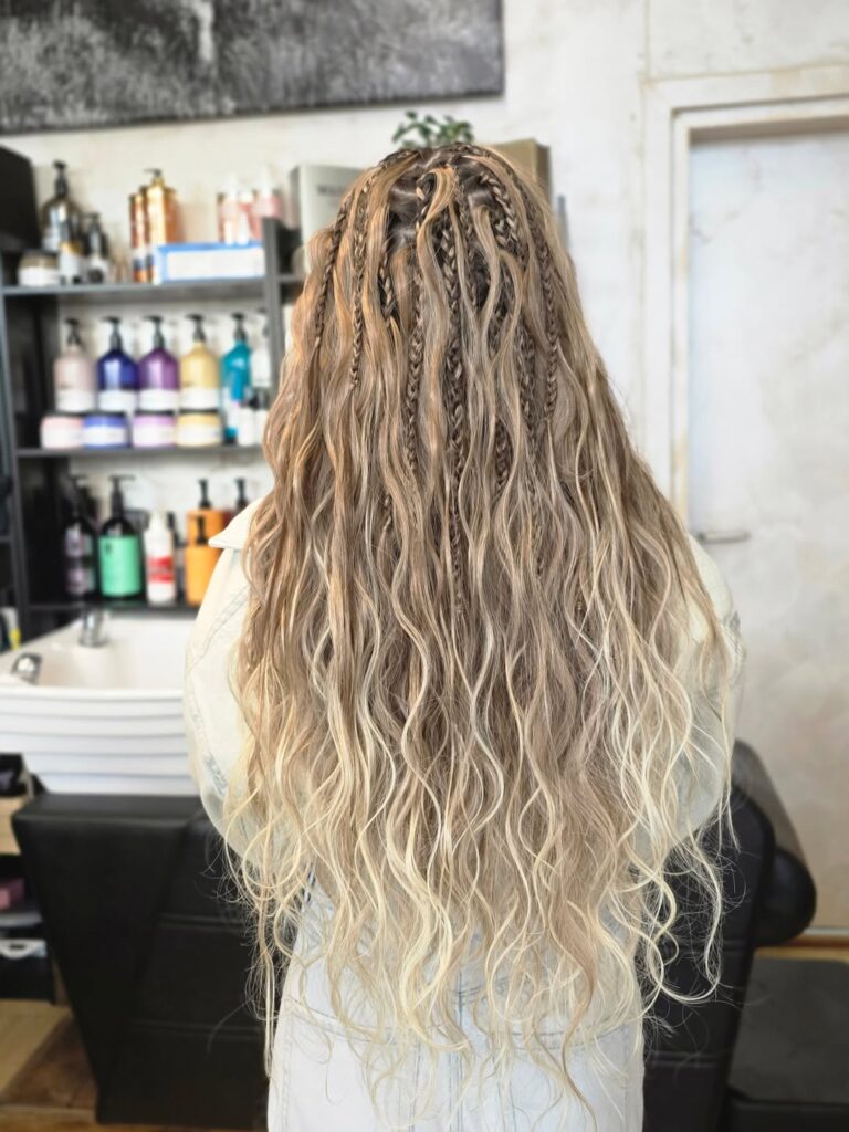 Long beachy blonde waves styled with several small accent braids throughout the hair.