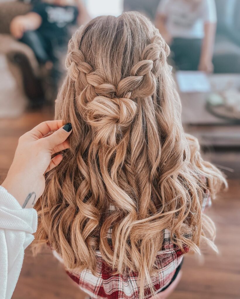 Long blonde curls styled with twisted braids pinned into a soft half up knot.