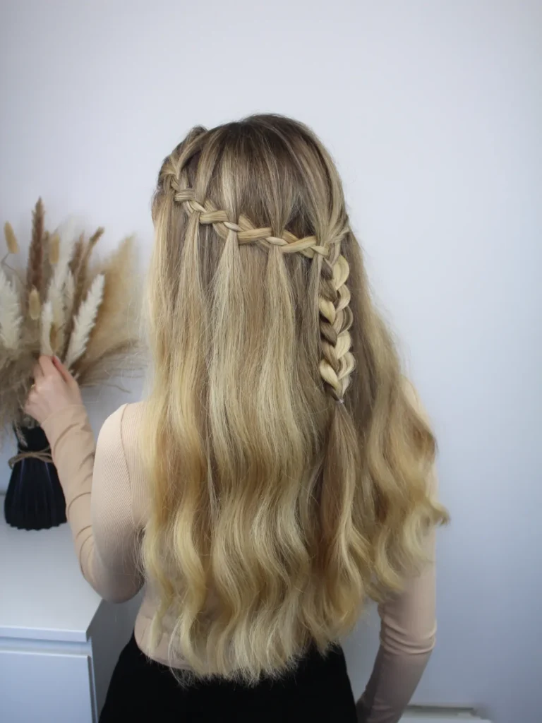 Long blonde wavy hair styled with a soft waterfall braid across the back.