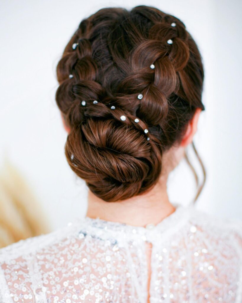 Brunette braided roll updo with pearl accents and smooth woven texture.