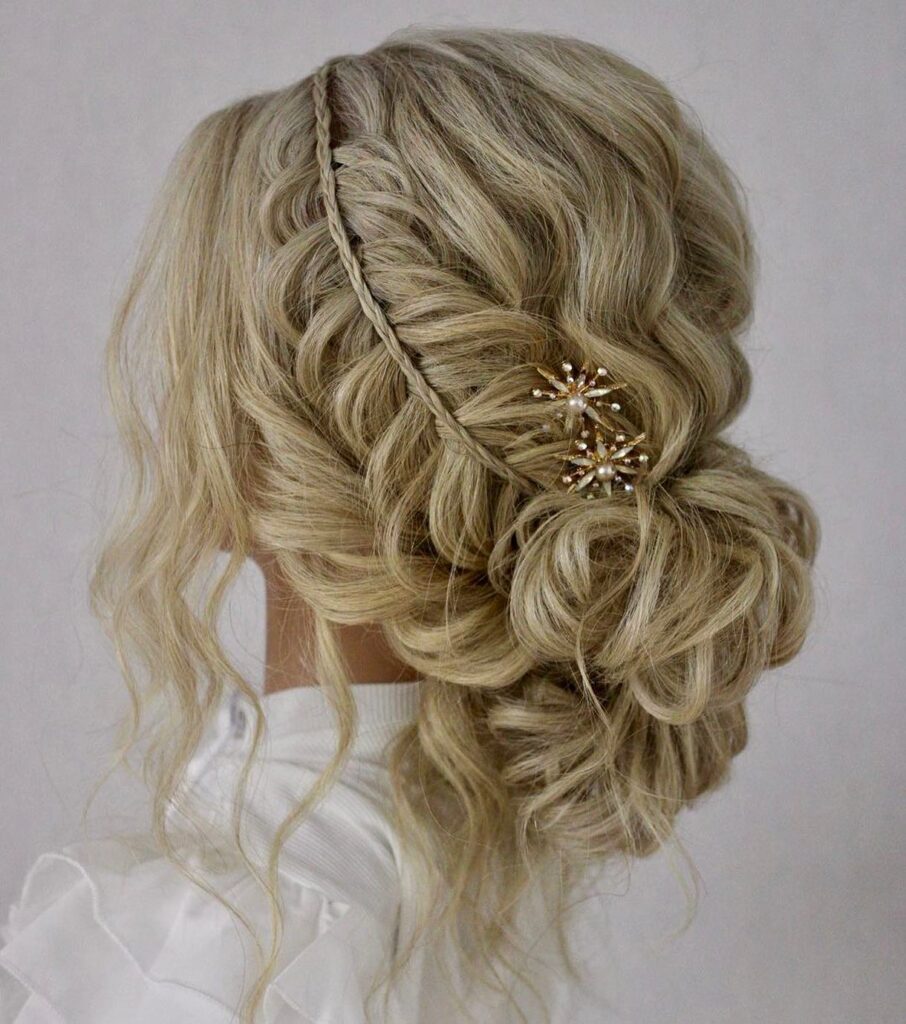 Loose blonde bridal updo with soft twists, a thin braid, and jeweled hair accessory.