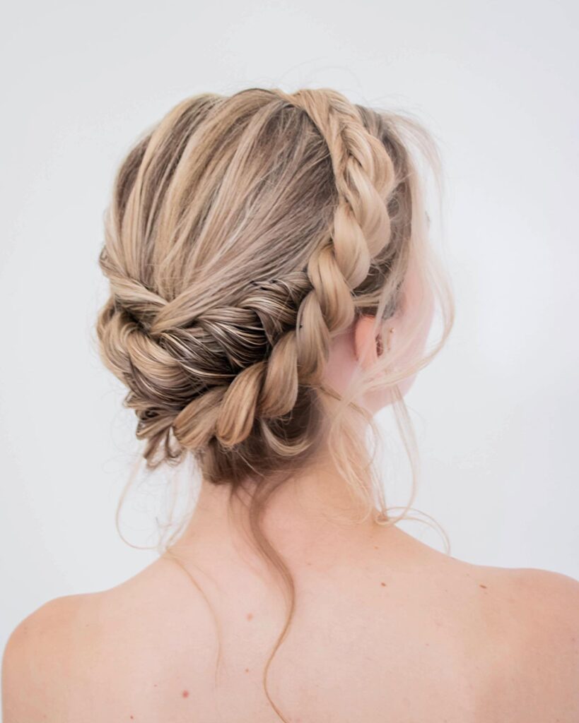 Elegant blonde braided updo with a thick side braid and twisted low bun.
