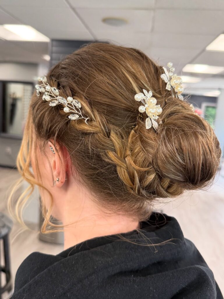 Brunette braided low bun with pearl hair accessories and soft highlights.