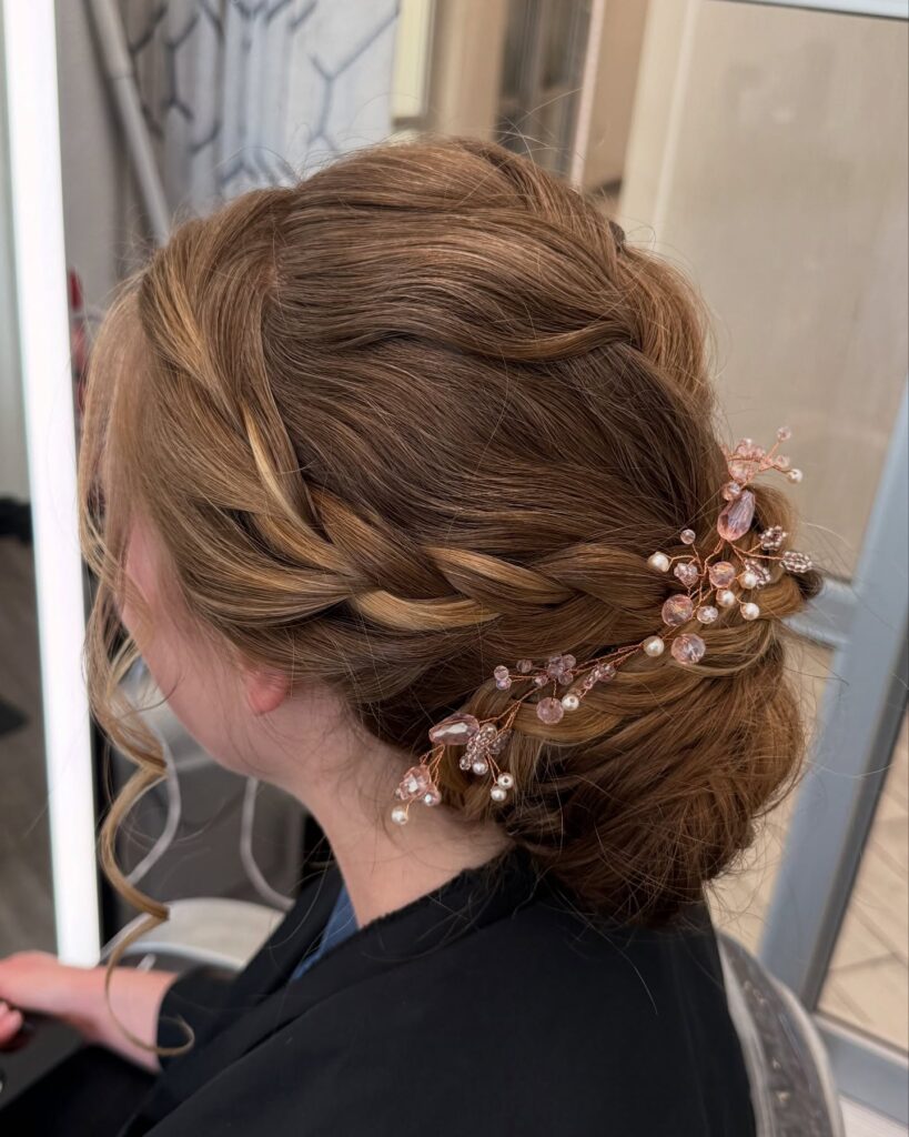 Brunette twisted low bridal bun with blush crystal hair accessory and loose curls.