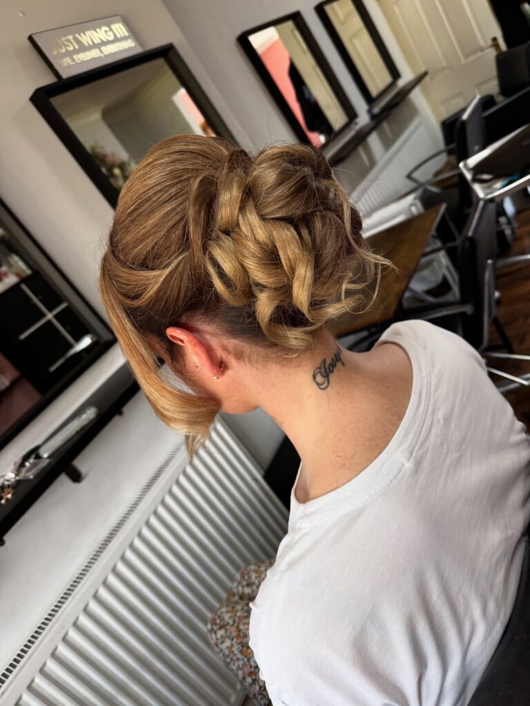 Loose twisted bridal updo with blonde highlights and textured low bun.