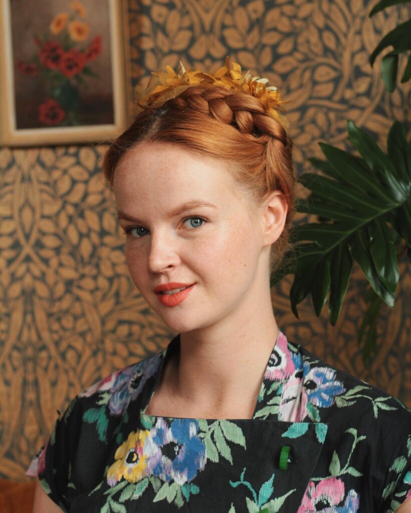 Copper red braided crown updo with a gold leaf headpiece and smooth finish.
