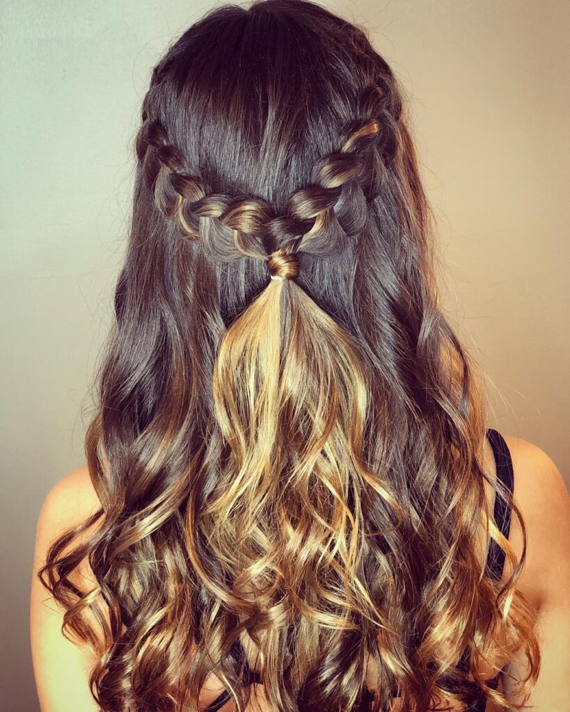 Half up hairstyle with side braids meeting at the back and long loose curls.
