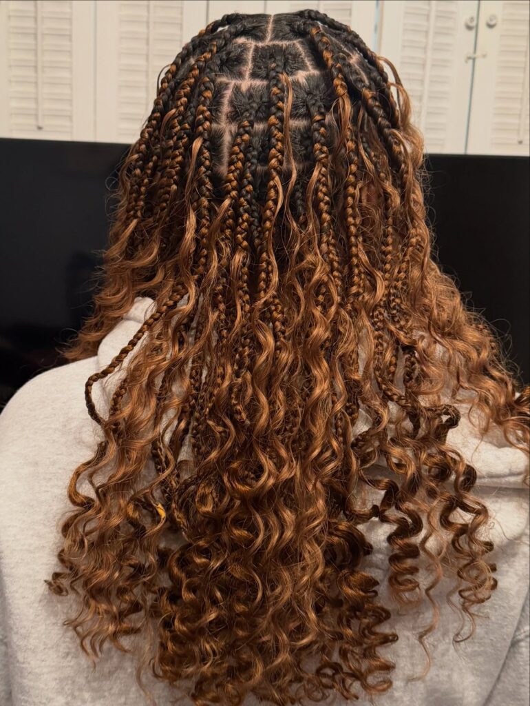 Boho braids with small plaits and voluminous curly hair throughout.