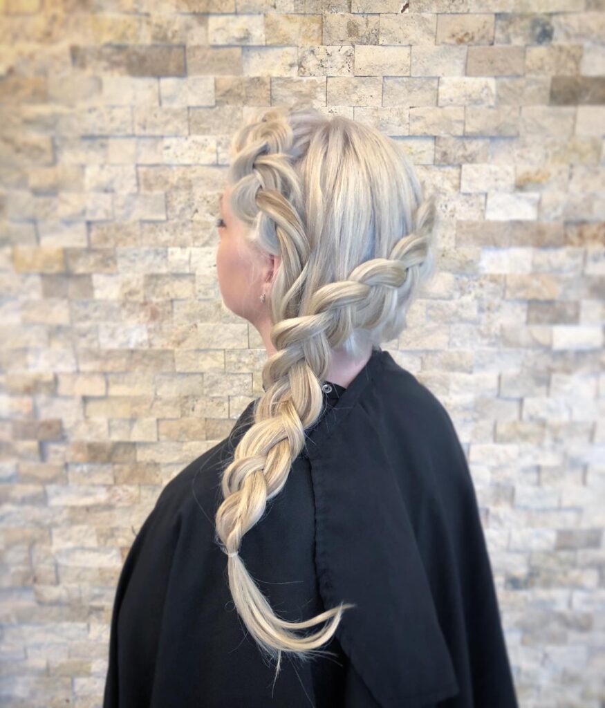 Platinum blonde side braid wrapped around the head and continuing into a long loose braid.