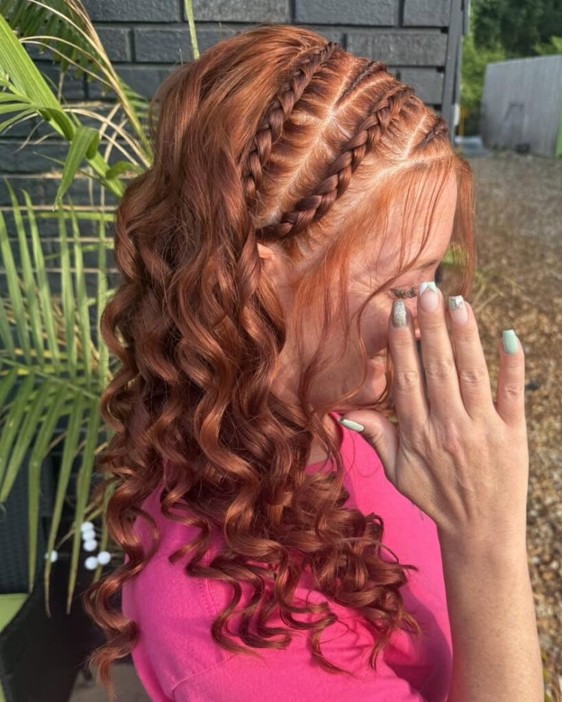 Half up hairstyle with small cornrow braids on top and long curly hair flowing down.