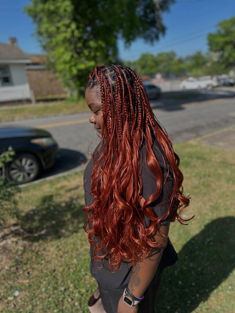 Auburn knotless braids transitioning into long loose wavy ends.