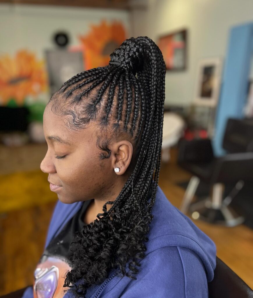 A high braided ponytail with neat feed in braids and curly ends.