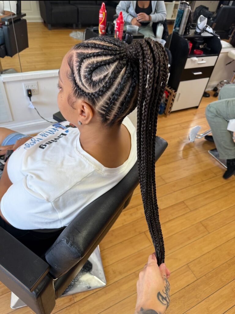 A braided ponytail with curved swirl braid patterns and long box braids.