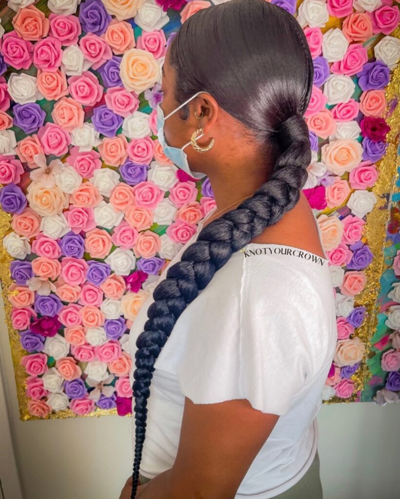 A sleek low ponytail styled into one oversized black braid.