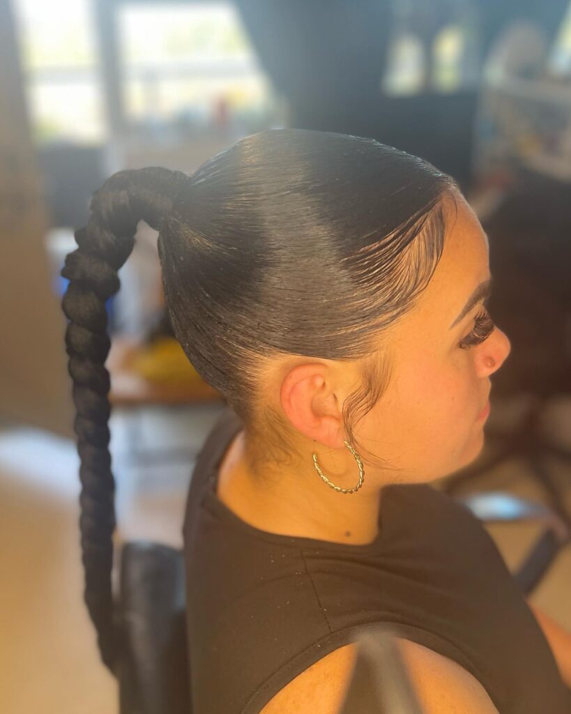 A sleek long ponytail styled into a thick bubble braid with smooth laid edges.