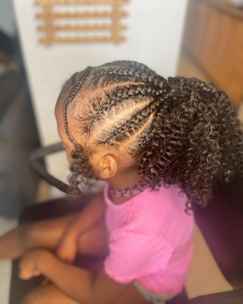 A braided ponytail for kids with detailed side braids and a curly puff ponytail.