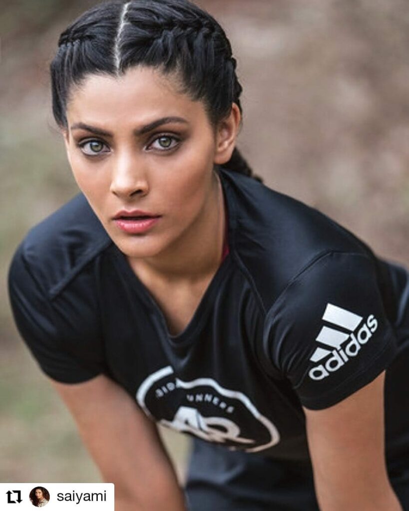 A woman wearing sleek dark cornrow braids and a black athletic shirt during a workout.