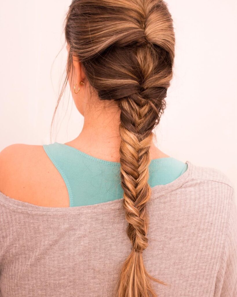 A long fishtail braid hairstyle with blended blonde highlights and a smooth polished finish.