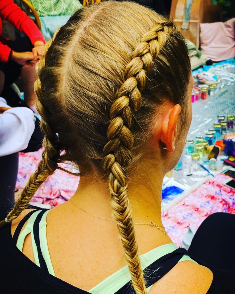 Back view of thick blonde Dutch braids transitioning into fishtail braid ends.