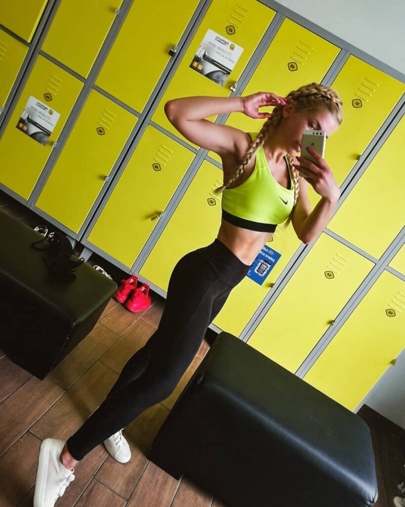 A woman in workout clothes wearing tight blonde boxer braids in a gym locker room.