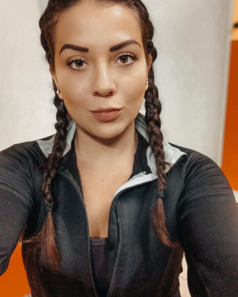 A woman with medium brown double braids wearing a black athletic jacket for a sporty everyday look.