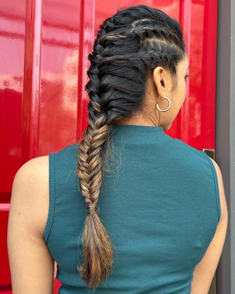 Back view of a side swept fishtail braid with dark brown hair and caramel highlights.