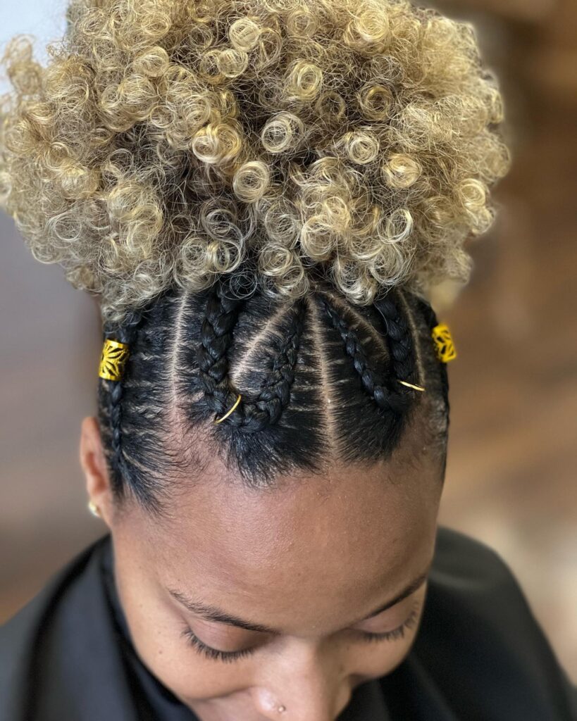 Blonde curly puff hairstyle with neat front braids and gold braid accessories.