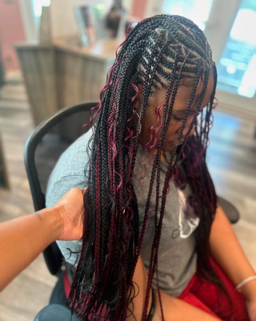Black braids with burgundy peekaboo highlights and curled accent strands.