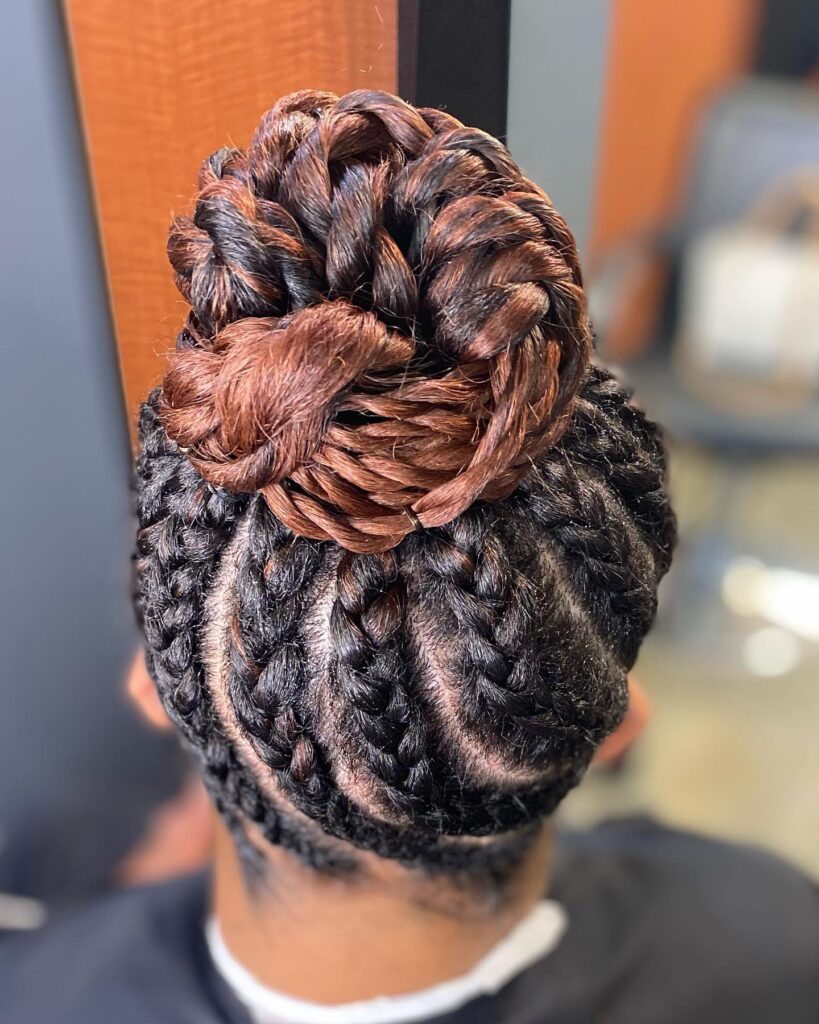 Braided updo with thick cornrows gathered into a large brown toned braided bun.