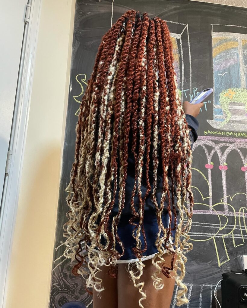 Extra long boho braids with auburn and blonde tones and curly textured ends.