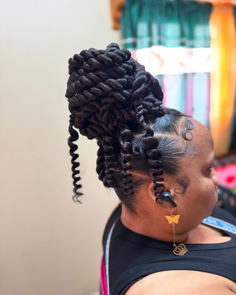 Large jumbo twist bun updo with curled tendrils and sleek styled edges.