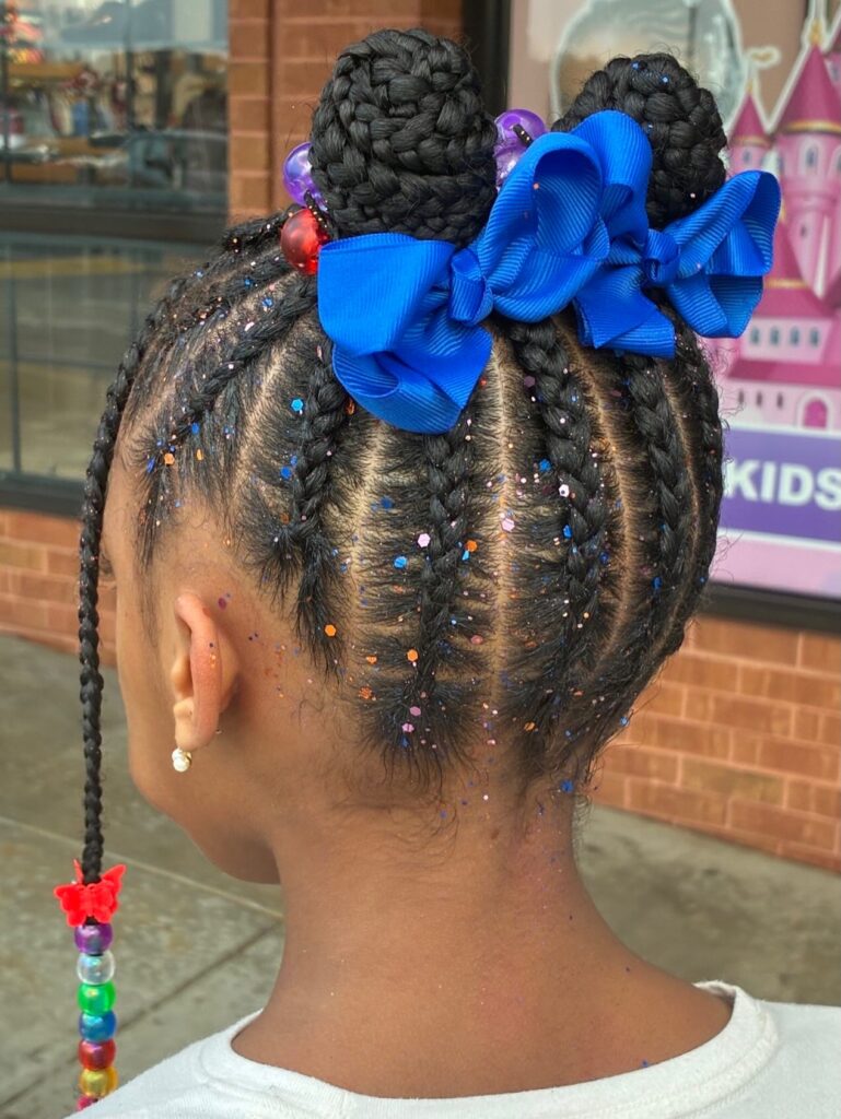 Kids braided hairstyle with two braided buns, blue bows, beads, and glitter accents.