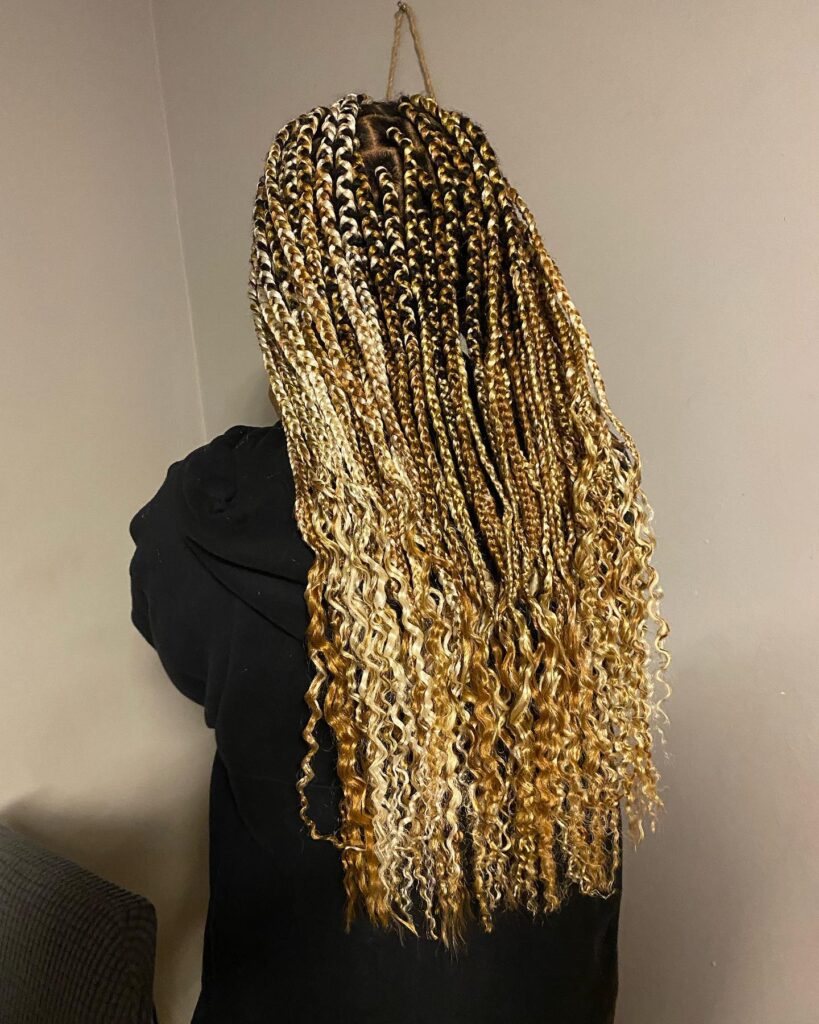 Blonde feed in braids flowing back into long loose curly ends without a ponytail.