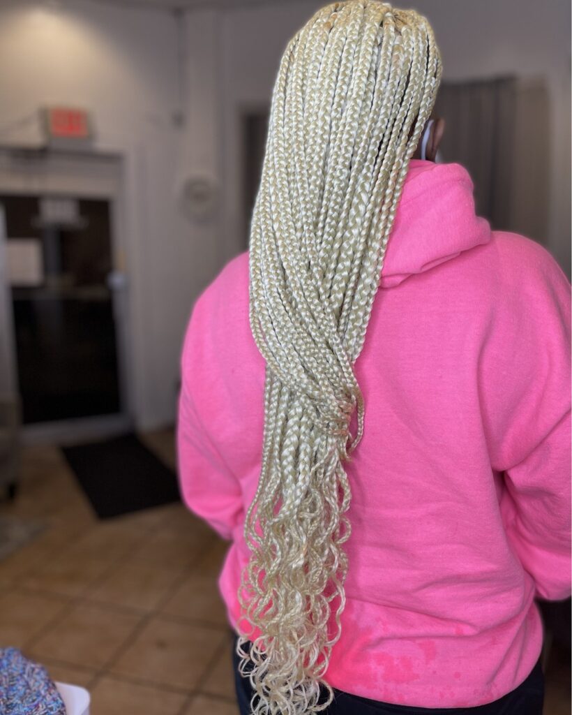 Long platinum blonde box braids with straight lengths and curly ends.