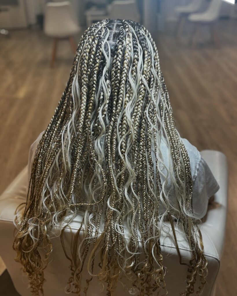 Blonde accent braids with loose wavy pieces framing the face.
