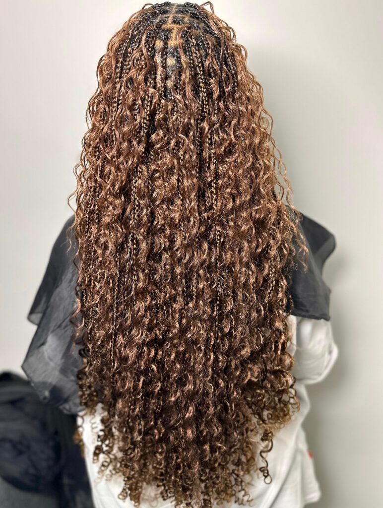 Long honey brown knotless braids with tight curly texture and volume.