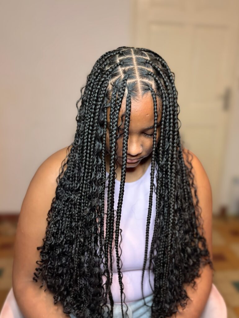 Knotless braids with face framing pieces and soft curly layered ends.