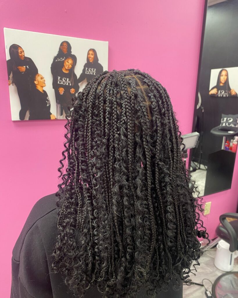 Shoulder length knotless braids with soft curls and natural black color.