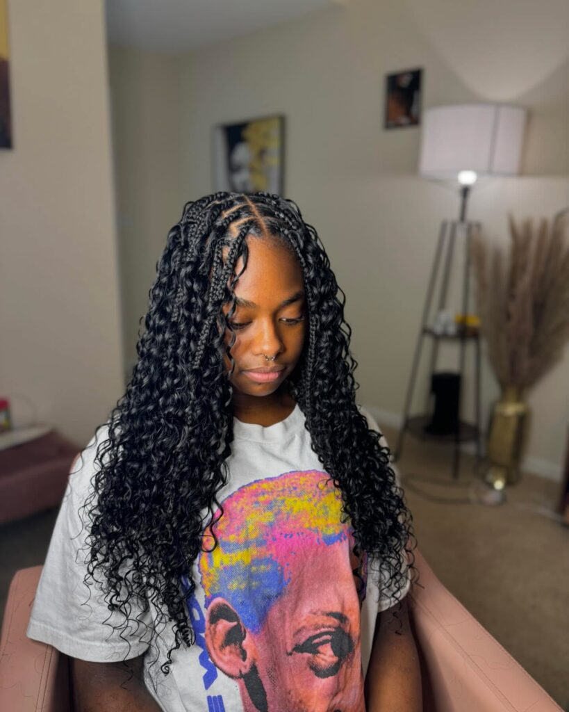 Knotless braids with loose spiral curls creating a full voluminous look.