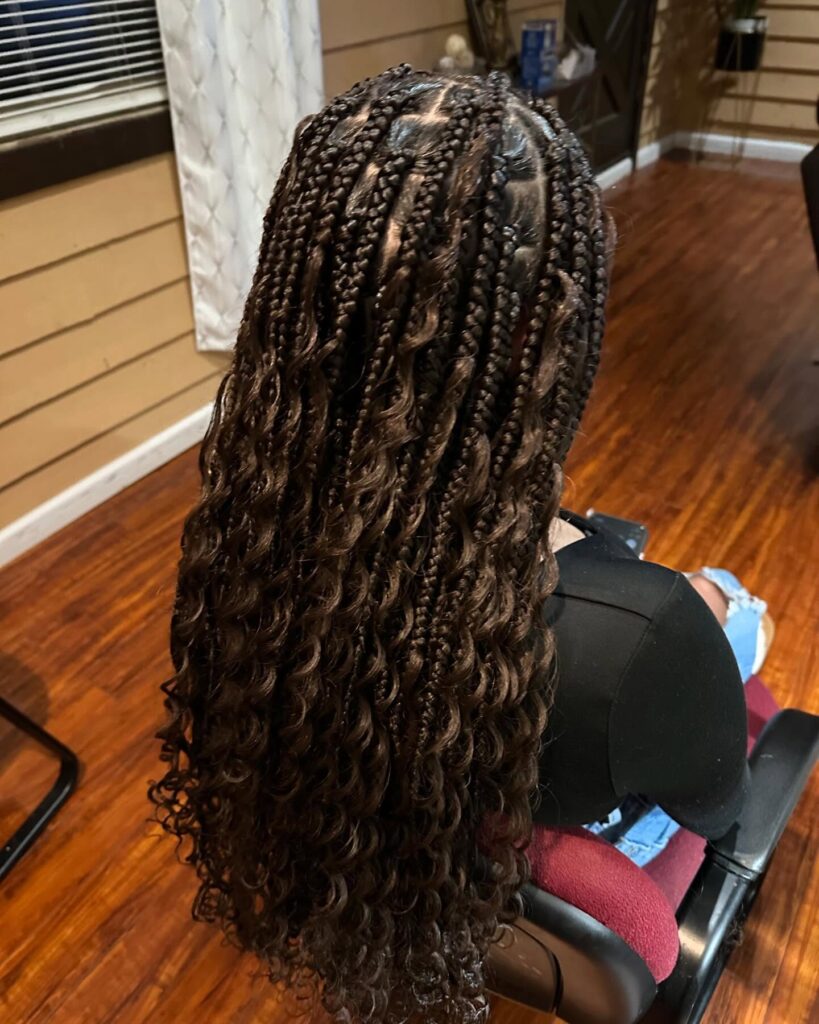 Brown knotless braids with loose glossy curls and warm dimensional tones.