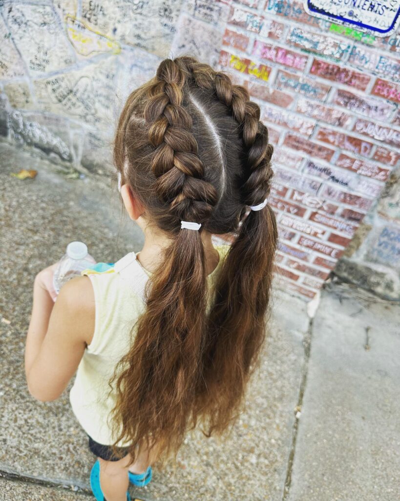 Chunky Dutch braided pigtails with loose wavy brunette ponytails.