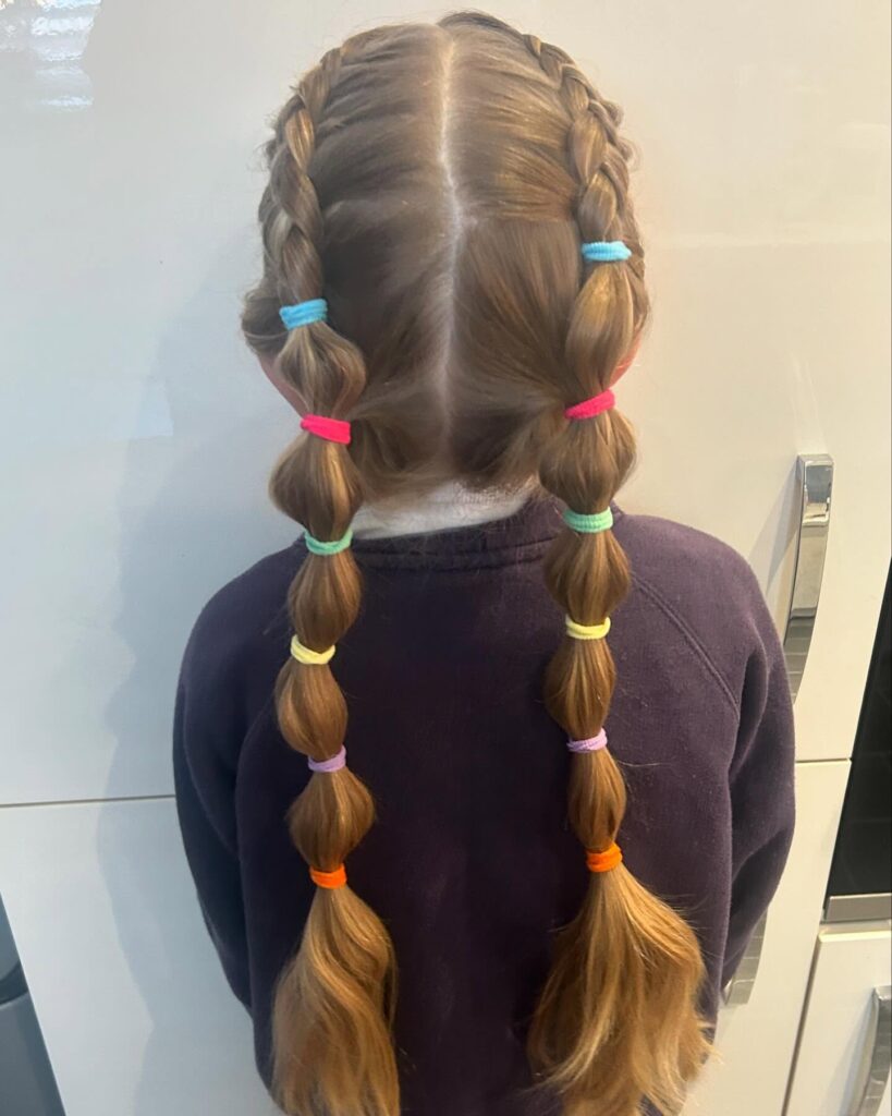 Bubble braided pigtails with colorful elastics and smooth light brown hair.
