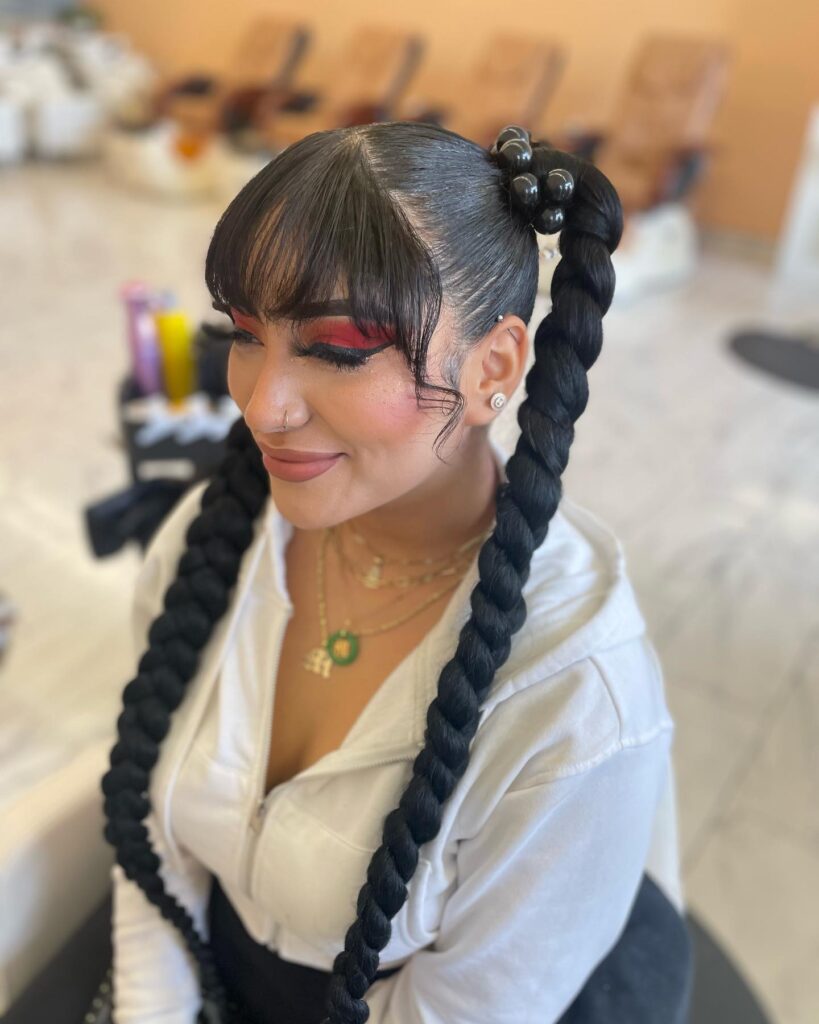 Long bubble braided pigtails with wispy bangs and sleek dark hair.