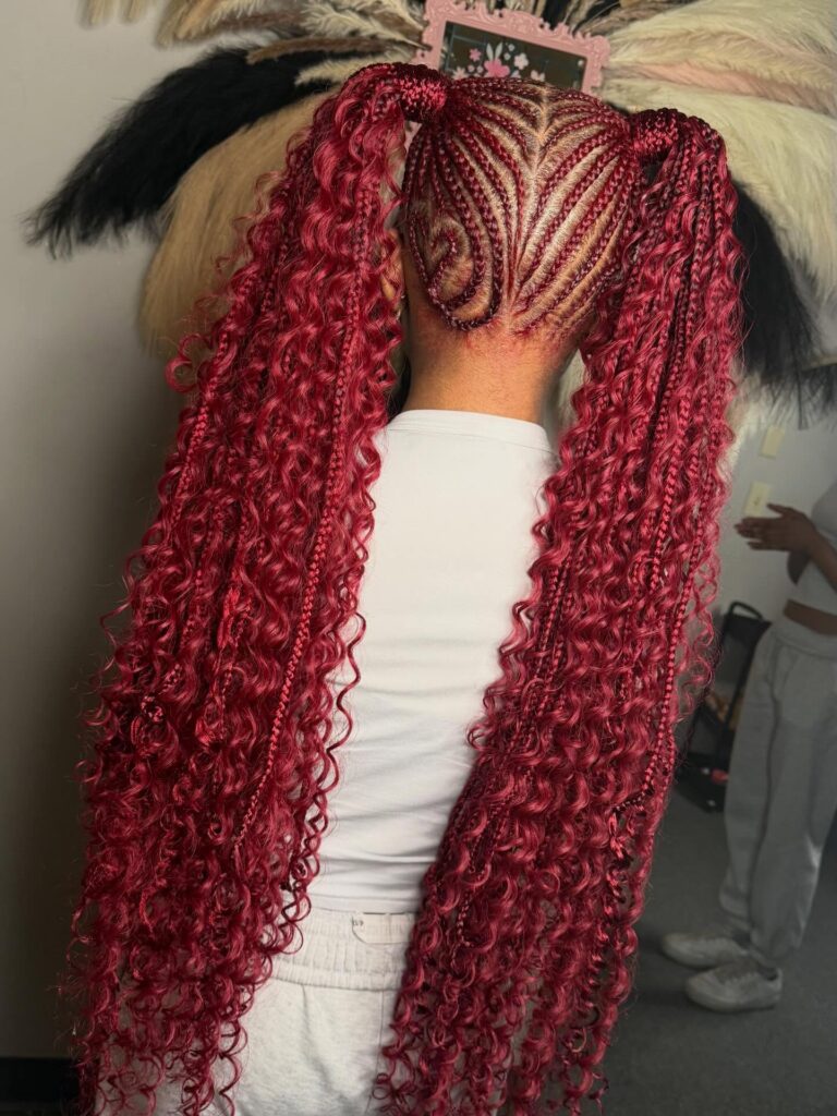 A woman with burgundy curly braided ponytails and detailed swirl braid patterns.