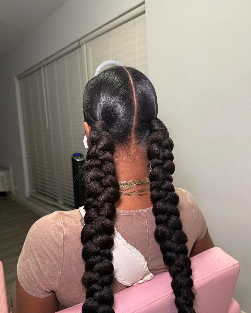 A woman with sleek two ponytails styled into chunky bubble braids.